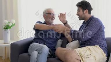 幸福的家庭和年长的父亲和儿子交谈，亲吻手与快乐的沙发